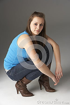 Teenage Girl Kneeling In Studio Stock Photo