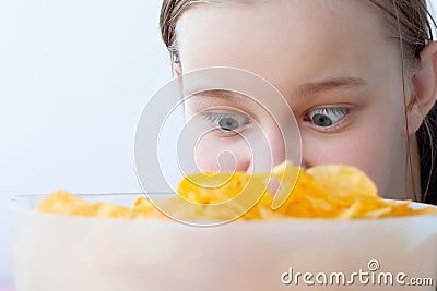 A teenage girl looks with wild, wide-open eyes at a bowl full of chips, face close-up Stock Photo