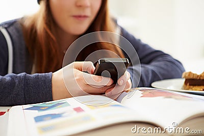 Teenage Girl Sending Text Message Whilst Studying Stock Photo