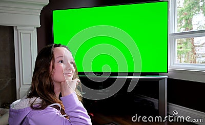 teenage girl sits admiringly in front of a big chroma key tv monitor ad enthusiastically points finger laughs thumbs up Stock Photo