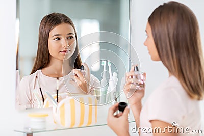 teenage girl spraying perfume at bathroom Stock Photo