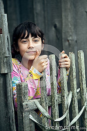 Teenage girl standing near vintage rural fence. Stock Photo