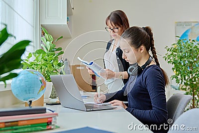 Teenage girl studying, female teacher with textbook helps tells teaches Stock Photo