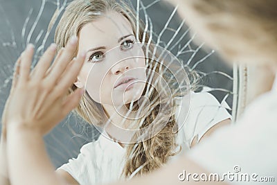 Teenage girl touching broken mirror Stock Photo