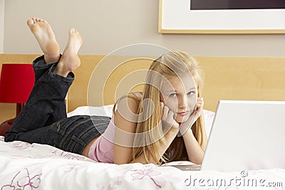 Teenage Girl Using Laptop In Bedroom Stock Photo