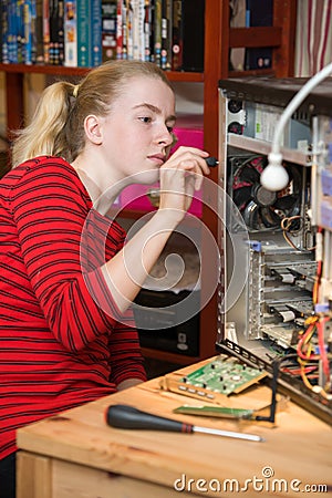 Teenage girl using a screwdriver to dismantle an open PC Stock Photo