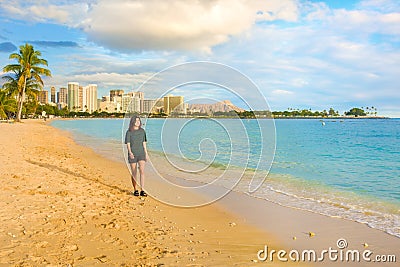 Teenage girl walking at empty Ala Moana Beach at sunset Stock Photo