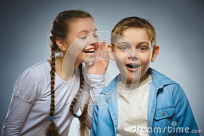 Teenage girl whispering in ear of boy on gray background. Communication concept Stock Photo