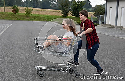 Teenage girlfriends having fun with shopping cart Stock Photo