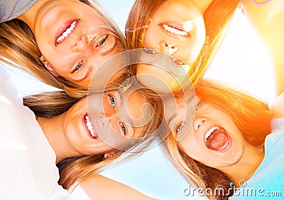 Teenage girlfriends staying together over blue sky Stock Photo
