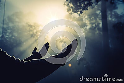 Teenage girls pray with a cross in a sunny nature. The girl sat in the green forest with sunlight. Stock Photo