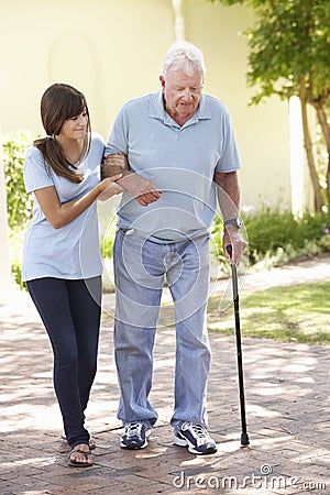 Teenage Granddaughter Helping Grandfather Out On Walk Stock Photo