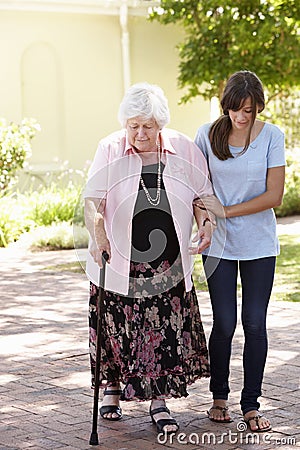 Teenage Granddaughter Helping Grandmother Out On Walk Stock Photo