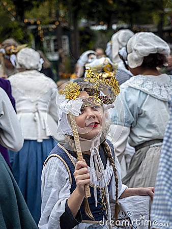 Teenage lady in traditional Danish costume holding up a venetian mask Editorial Stock Photo