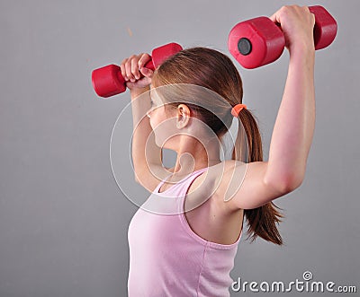 Teenage sportive girl is doing exercises to develop muscles on grey background. Sport healthy lifestyle concept. Sporty Stock Photo