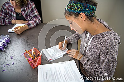 Teenage student girls studying from textbooks and writing notes in notebooks Stock Photo
