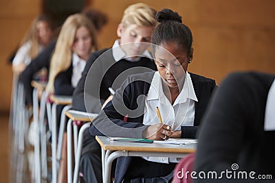 Teenage Students In Uniform Sitting Examination In School Hall Stock Photo