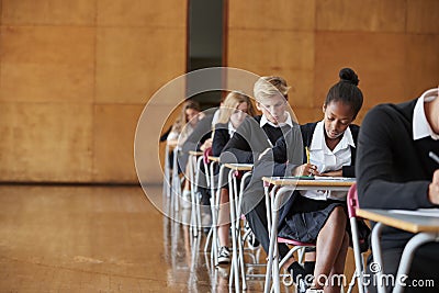 Teenage Students In Uniform Sitting Examination In School Hall Stock Photo