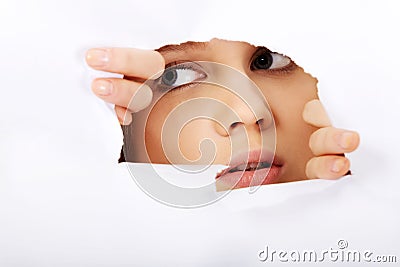 Teenage woman peeping through hole on paper Stock Photo