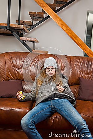 Teenaged girl sitting on sofa and eat chocolate - Lazy to do anything - Mornings are difficult Stock Photo