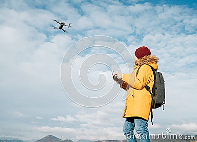 Teenager boy dressed yellow jacket piloting a modern digital drone using remote controller Stock Photo