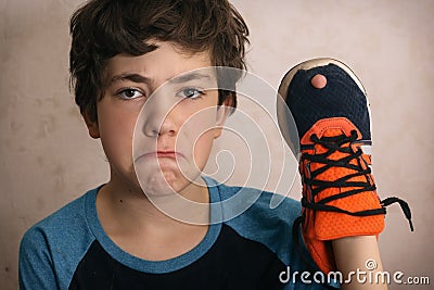 Teenager boy frustrated about hole in his favourite trainers shoes Stock Photo