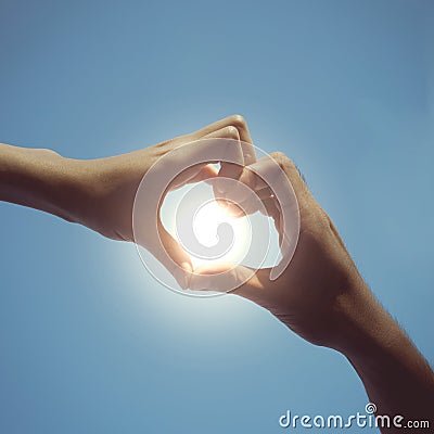 Teenager boy and girl hands in heart form love in blue sky Stock Photo