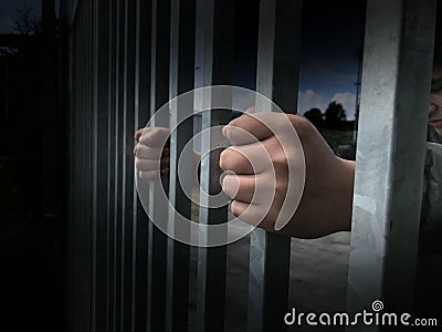 Teenager boy hands holding strong iron bars. Immigrant and refugee crisis. Dramatic border fence or prison concept Stock Photo