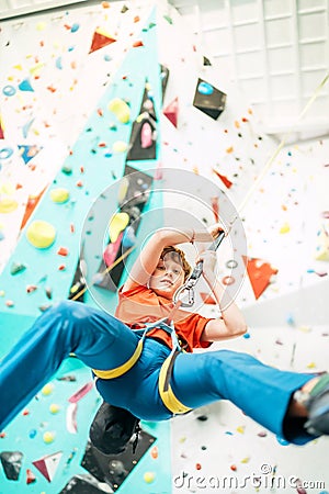 Teenager boy at indoor climbing wall hall. Boy is climbing using an auto belay system and climbing harness. Active teenager time Stock Photo