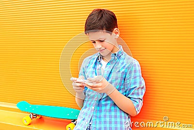 teenager boy uses smartphone, skateboard on a colorful orange Stock Photo