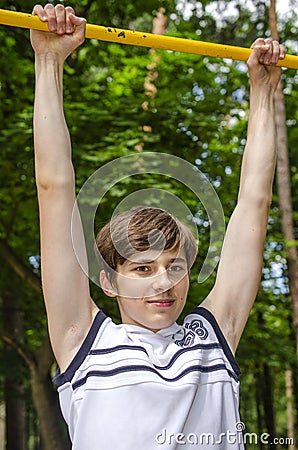 Teenager boy pulls up on a horizontal bar Stock Photo