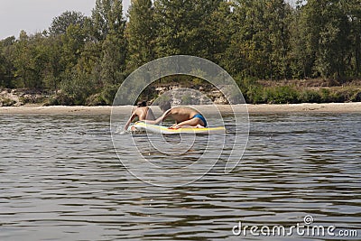 Teenager boys surfing on tropical beach in Europe. Kids on surf board on river wave. Active water sports for kids. Kid swimming Editorial Stock Photo