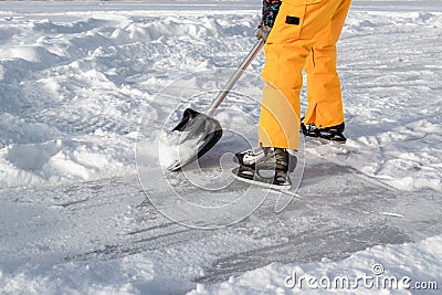 Teenager brush snow with shovel on ice of forest lake for ice skating. Healthy lifestyle Stock Photo