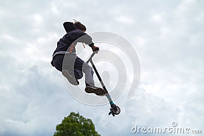 Teenager did unsuccessful trick on sportive push scooter on a city sports ground Stock Photo