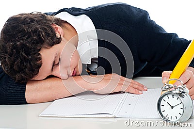 Teenager dozing off while writing his test Stock Photo