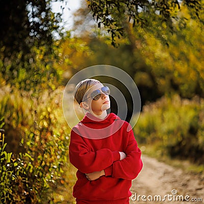 A teenager in a fall park pondered. A boy in a red suit in a park in the fall Stock Photo