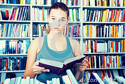 Teenager girl brunete looks for the right book in library Stock Photo