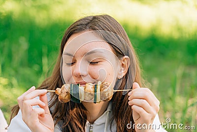 Teenager girl eating grilled vegetables outdoors. Vegan picnic with mushrooms and zucchini Stock Photo