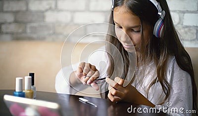 Girl in headphones chatting online on phone making manicure cutting nails with free and copy space Stock Photo