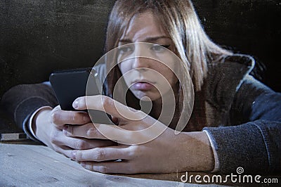Teenager girl looking worried and desperate to mobile phone as internet stalked victim abused cyberbullying stress Stock Photo