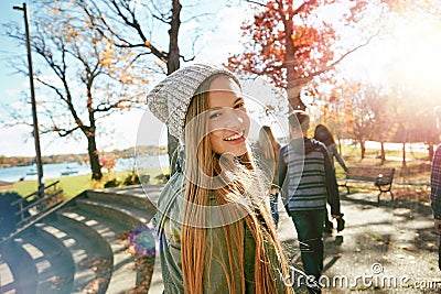 Teenager, girl in nature with friends and walk in park with autumn and sunshine, wellness with happy in portrait. Youth Stock Photo