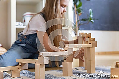 Teenager girl playing track constructor block tower with metallic ball Maria Montessori materials Stock Photo