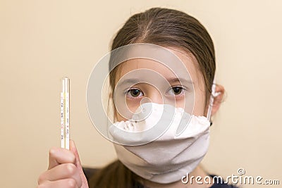 Teenager girl in a protective mask with a thermometer in hand Stock Photo