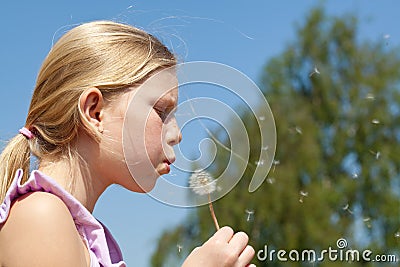 Teenager girl puffing to dandelion Stock Photo