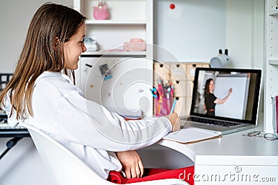 Teenager girl studying online at home looking at teacher giving lesson at laptop screen at quarantine isolation period. Stock Photo