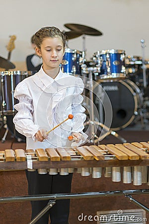 Teenager girl in a white shirt boy playing the marimba. Vertical photo Stock Photo
