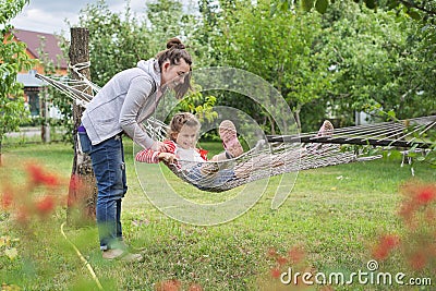 Teenager girls and child having fun in garden on hammock Stock Photo