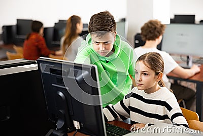 Teenager guy helps girl solve problem on computer in school class Stock Photo