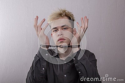 A teenager in handcuffs on a gray background. juvenile delinquents in quarantine, criminal liability. Members of youth criminal gr Stock Photo