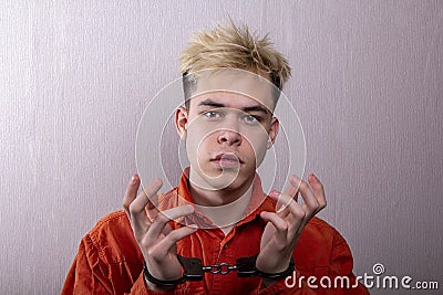 A teenager in handcuffs on a gray background. juvenile delinquents in quarantine, criminal liability. Members of youth criminal gr Stock Photo